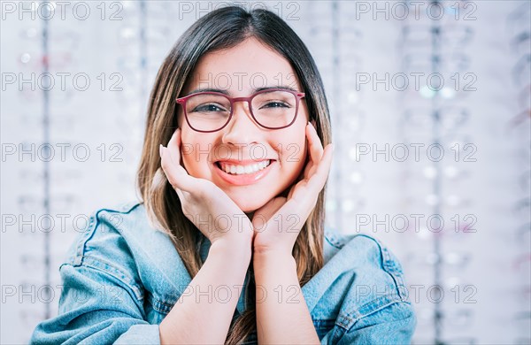 Portrait of beautiful girl modeling glasses in an optical store. Happy girl modeling glasses in an optical lens store
