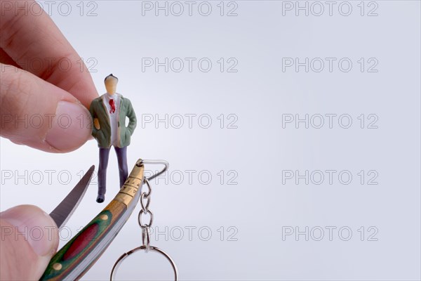 Hand holding a pocket knife near a human figure on a white background