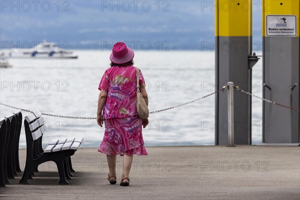 Tourist in colourful clothes on the jetty at Lake Constance