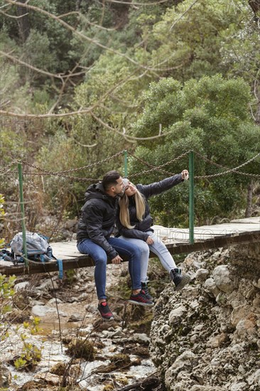 Couple with backpack sitting bridge