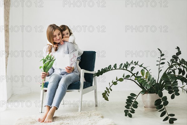 Daughter hugging mother with greeting card