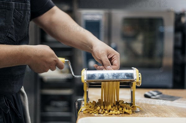Male chef using machine chop fresh pasta dough