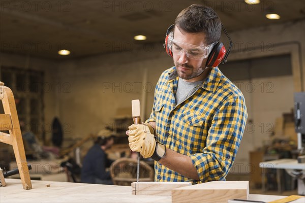 Close up carpenter hitting hammer chisel wooden block workshop