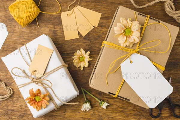 Wrapped gift tied with tag string beautiful flower wooden surface