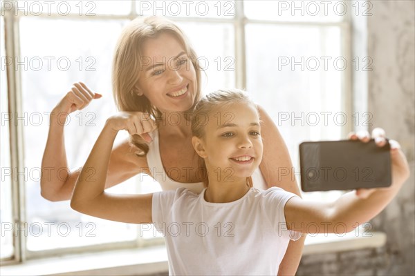 Mother daughter taking selfie flexing arm muscles