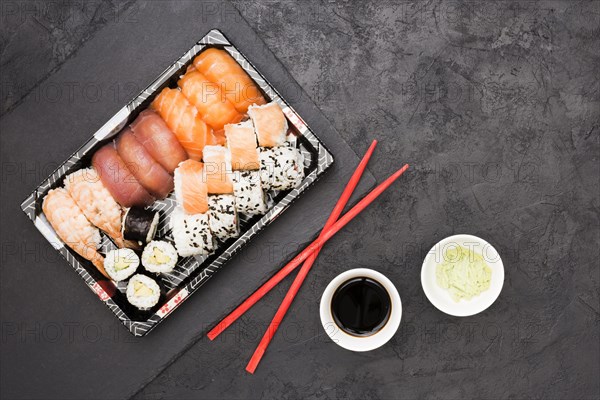 Vivid asian fish rolls tray chopsticks with soya sauce wasabi back concrete floor