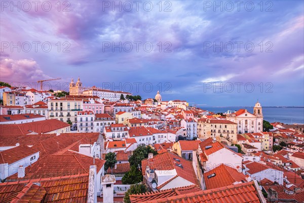 View of Lisbon famous view from Miradouro de Santa Luzia tourist viewpoint over Alfama old city district on sunset with dramatic overcast sky. Lisbon