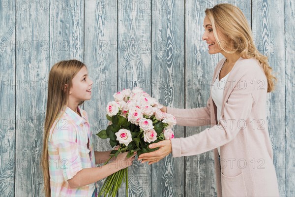 Daughter presenting mother bouquet roses
