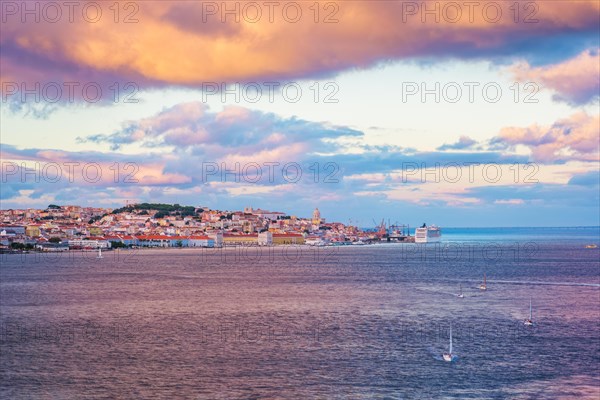 View of Lisbon over Tagus river from Almada with yachts tourist boats and moored cruise liner on sunset with dramatic sky. Lisbon