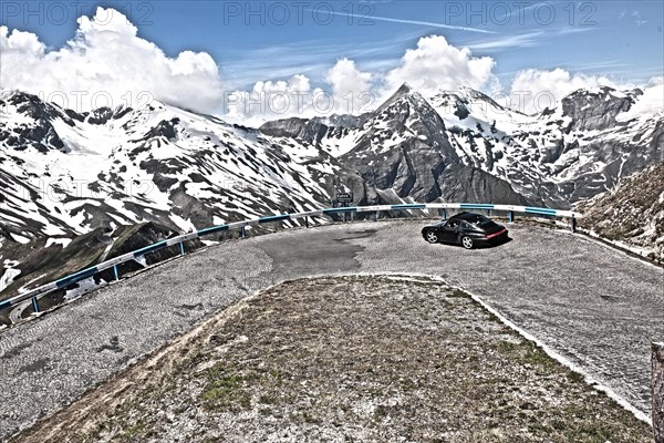 Photo with reduced dynamic range saturation HDR of view of Porsche 911 993 driving into hairpin bend 5 of historic old Grossglockner High Alpine Road Grossglockner-Hochalpenstrasse with cobblestones m...
