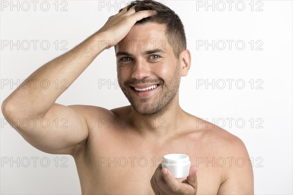 Portrait happy man applying hair wax standing against white background