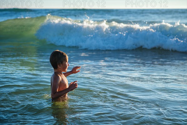 Boy has fun enjoys jumps dives in ocean sea waves of Atlantic Ocean. Fonta da Telha beach