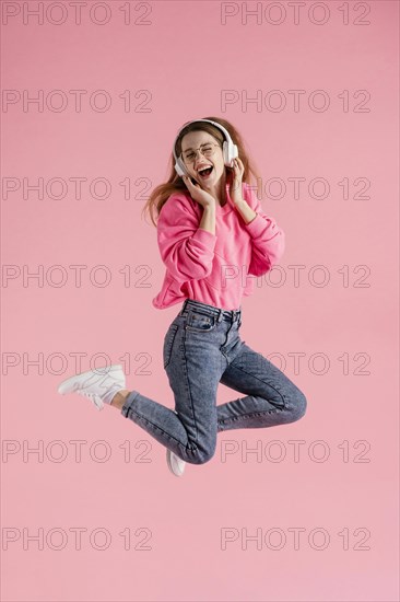 Portrait happy woman jumping listening music