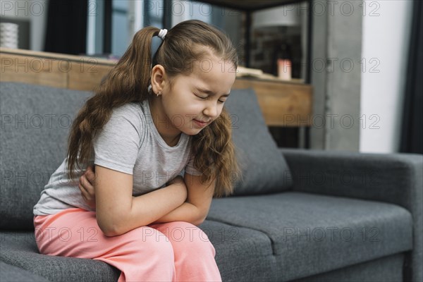 Little girl holding hands her stomach suffering from pain