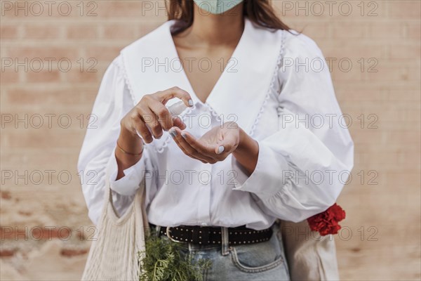 Front view woman with face mask using hand sanitizer