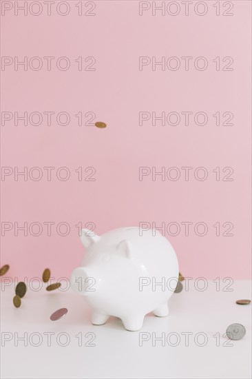 Coins falling white piggybank desk