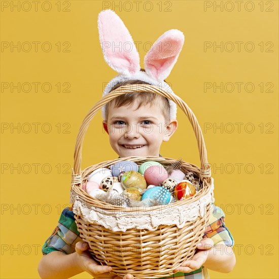 Little boy holding basket with painted eggs