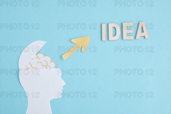 Open paper human head with yellow arrow pointing word idea blue background