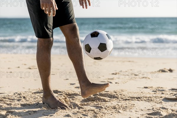 Male tossing ball up playing game beach