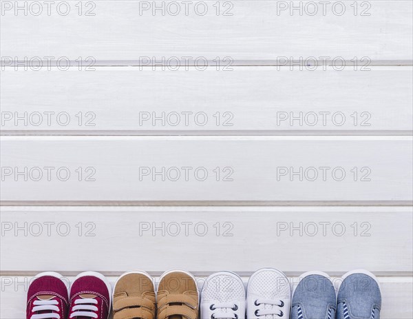 Baby concept with four pairs shoes space wooden surface