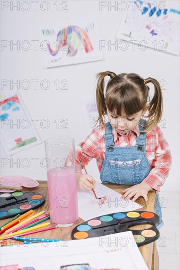 Cute girl painting with aquarelle paper