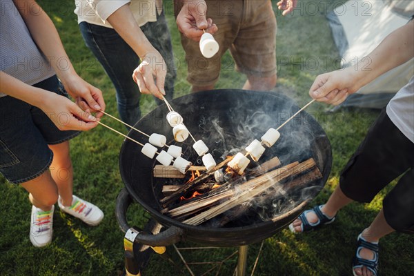 Elevated view hands roasting marshmallow barbecue fire
