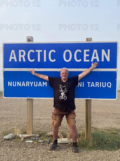 Tourist in front of sign Arctic Ocean