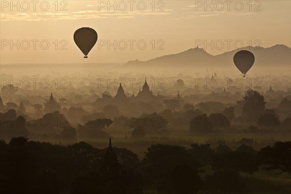 Hot air balloons over landscape with stupas
