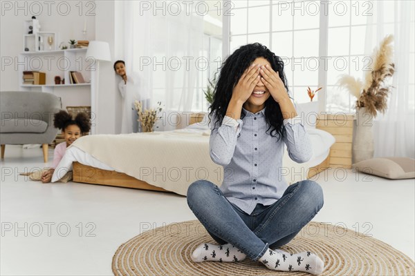 Front view smiley mother playing hide seek with her children home