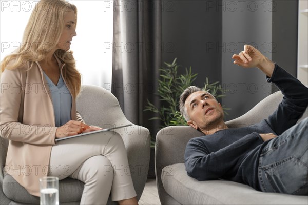 Mid shot man laying couch therapy cabinet near counselor