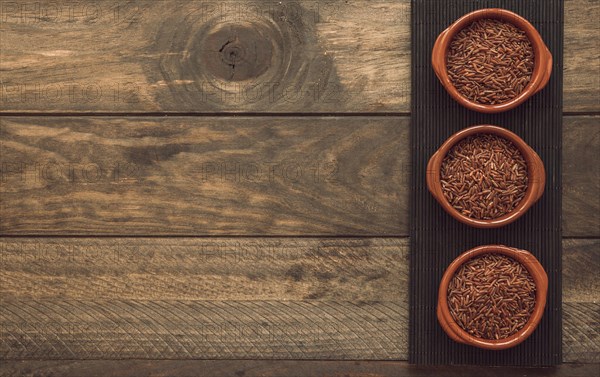 Uncooked red jasmine rice bowls placemat wooden background