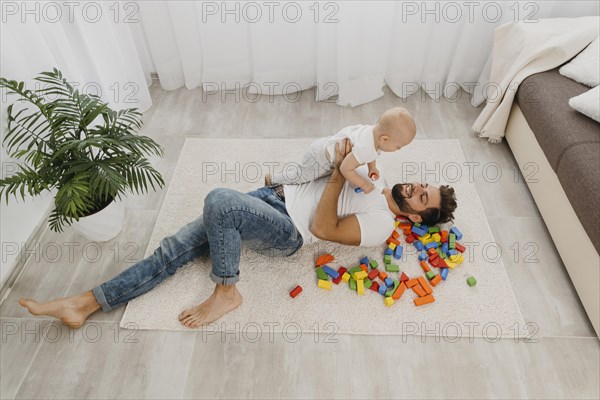 High angle father playing floor home with baby