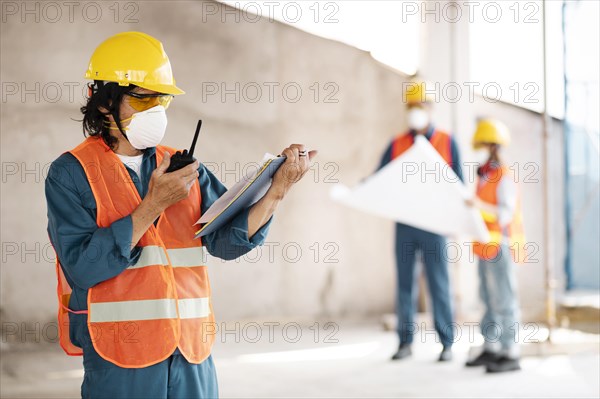 Colleagues with safety equipment working with blueprints