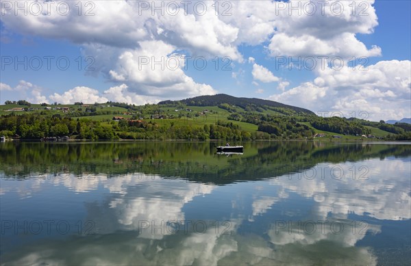 (Cumulus) clouds with fishing boat reflected in the Irrsee, Zell am moss, Salzkammergut, Upper