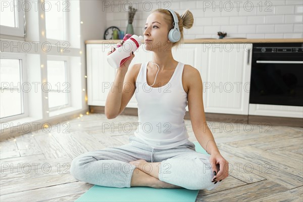 Female mat with headphones drinking water