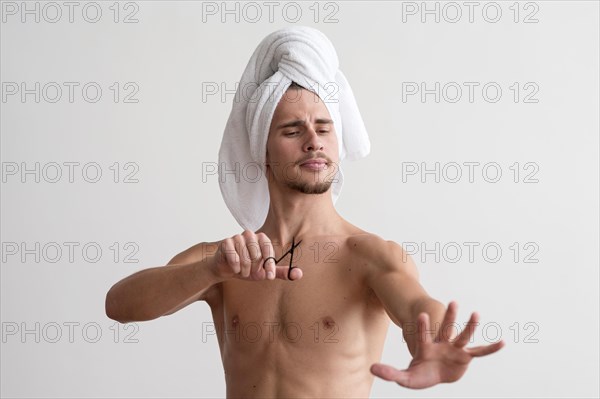 Front view shirtless man with towel his head looking his fingernails