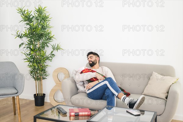Young handsome man sleeping sofa with his baby hand home
