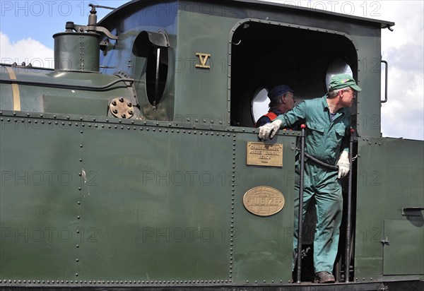 Engine driver driving steam train at the depot of the Chemin de Fer a Vapeur des Trois Vallees at Mariembourg
