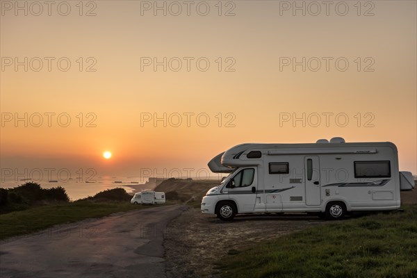Motorhomes parked along the coast at sunset with view over the sea