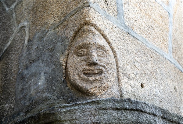 Carved face in granite block on corner of building