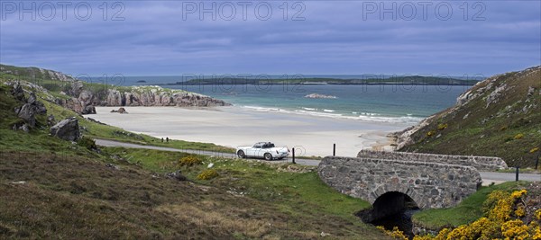 Car driving on desolate road past Ceannabeinne Beach in summer near Durness