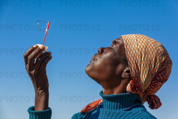 African woman making soap bubbles