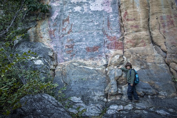 Boy in front of rock rock painting