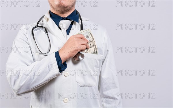 Dishonest doctor putting money in pocket. Corrupt doctor putting bribe money in pocket isolated. Medical bribery concept