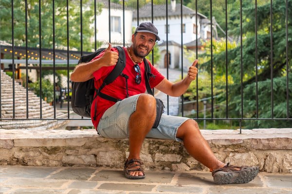 Portrait of a smiling tourist sitting resting on a viewpoint the city of Gjirokaster or Gjirokastra. Albanian
