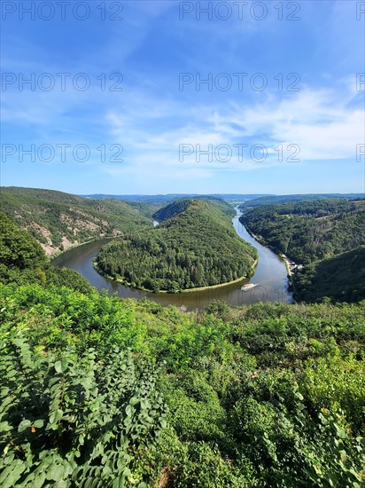 Aerial view of the Saar Loop. The Saar winds through the valley and is surrounded by green forests. Orscholz