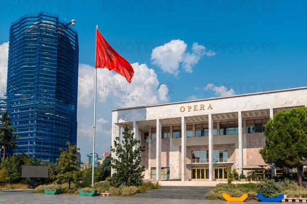 Palace of Culture or Opera on Skanderbeg Square in Tirana and the flag of Albania moving in the wind