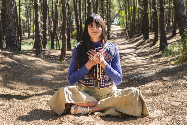 Portrait of an adult woman meditating with folded hands on her chest