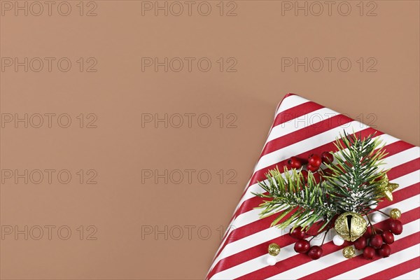 Striped Christmas gift box with seasonal decoration in corner of brown background with empty copy space