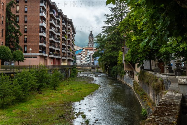 Traditional houses in the town of Azkoitia next to the Urola river and Church of Santa Maria La Real in the background